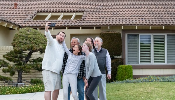 Multigenerational family taking a photo outside their home, illustrating the need for a family co-ownership agreement