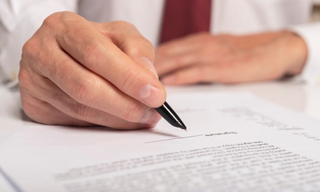 Hand with pen signing document