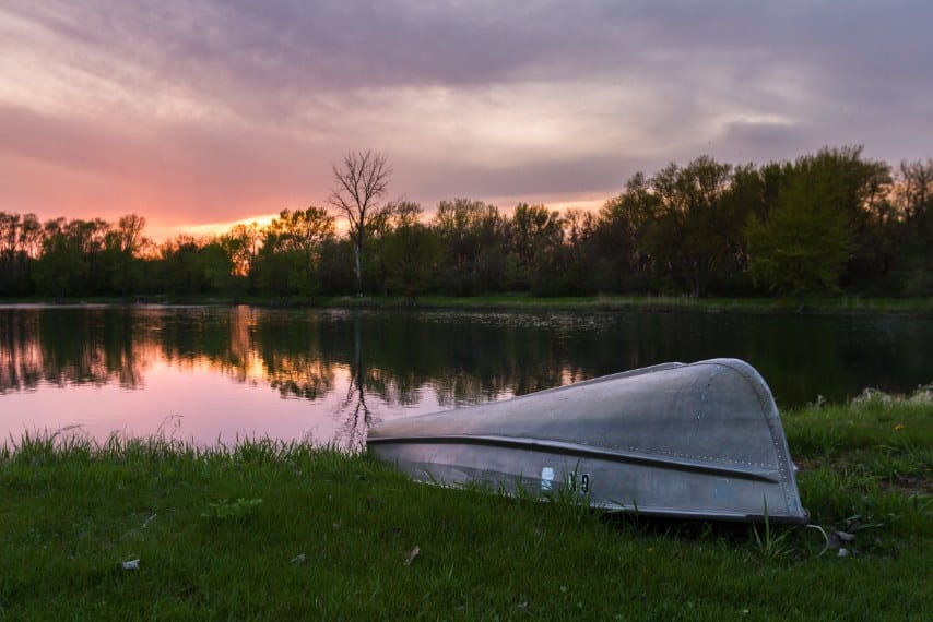 aluminum boat on water edge of pond