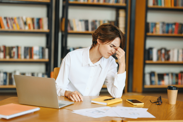 women at desk upset looking away from laptop and papers