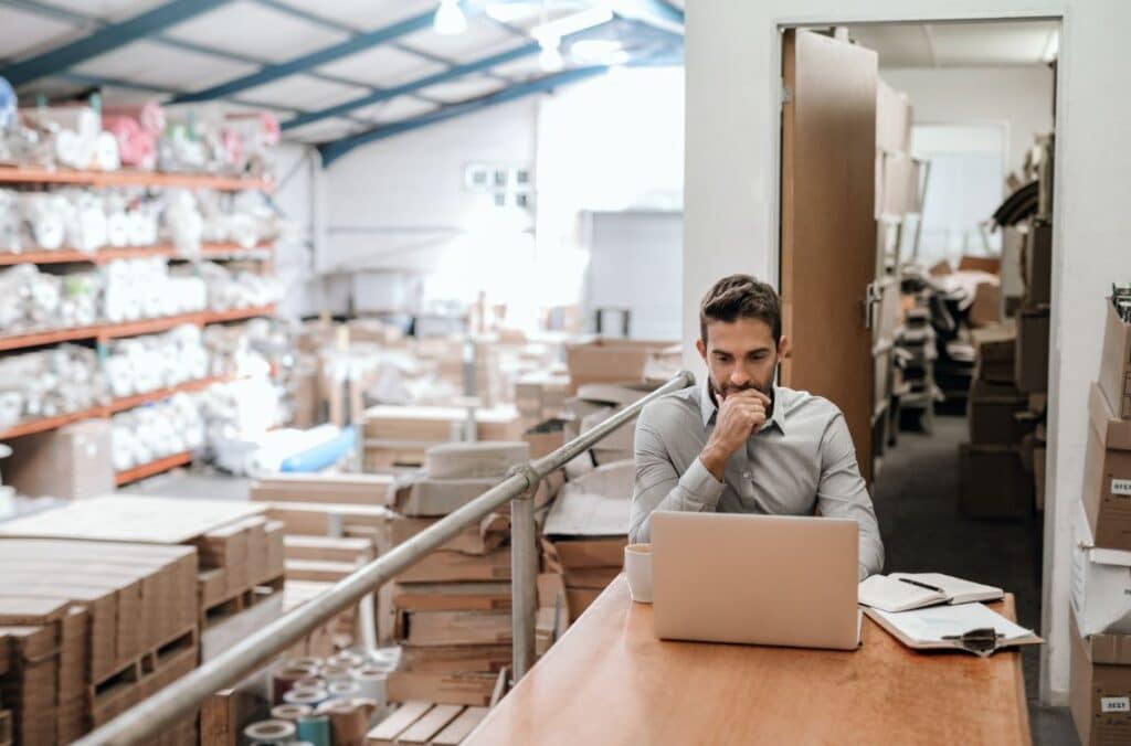 business owner in warehouse looking at computer