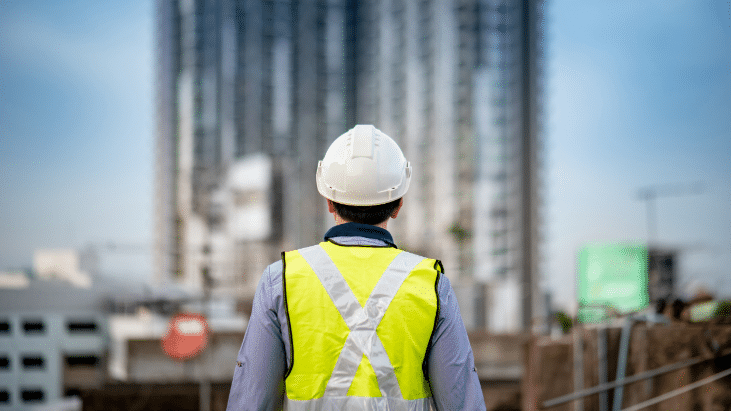 contractor in hardhat looking up at exposed steel in building